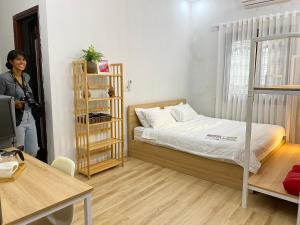 a woman standing in a small room with a bed at Lu Peaceful Homestay in Da Nang