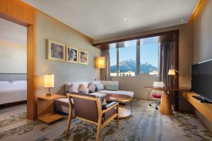 a hotel room with a couch and a table and a television at Hilton Garden Inn Lijiang in Lijiang