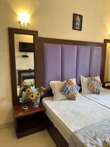Dormitorio con cama con cabecero púrpura y espejo en Hotel Riverside, en Baga
