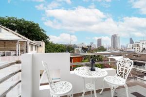 Un balcón con dos sillas y una mesa. en Capitel Rama 4, en Bangkok