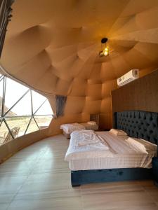 a bedroom with a large wooden ceiling with two beds at Wadi Rum Mars Camp in Wadi Rum