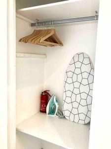 ein Schrank mit einem Regal mit einem Spiegel und einem Feuerlöscher in der Unterkunft 2 min de la Plage, Parking, Terrasse & Wifi! in Six-Fours-les-Plages