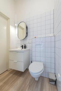 een witte badkamer met een toilet en een spiegel bij 66STORIES Studios in Kaunas