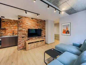 a living room with a blue couch and a brick wall at Urban Apartment Deluxe Szczecin Dąbie in Szczecin