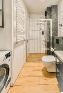 a bathroom with a shower and a toilet and a washing machine at Urban Apartment Deluxe Szczecin Dąbie in Szczecin