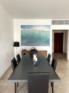 a dining room with a black table and chairs at Jabal Sifah Tha Marina View Apartment in Muscat