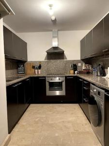 a kitchen with black cabinets and a stove at Jabal Sifah Marina View Apartment in Muscat