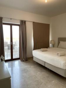 a bedroom with a large bed and a balcony at Jabal Sifah Tha Marina View Apartment in Muscat