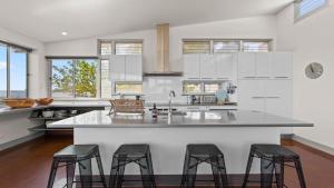 a kitchen with white cabinets and a large island with bar stools at Walshys Shack in Coffin Bay