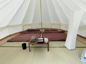 Una cama en una tienda con una mesa. en Glanchette岡山∼グランピング＆オートキャンプ∼, 