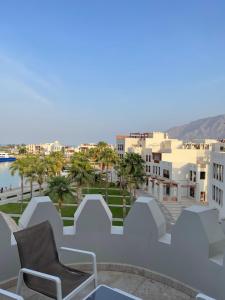 einen Stuhl auf einem Balkon mit Stadtblick in der Unterkunft Jabal Sifah Tha Marina View Apartment in Muscat