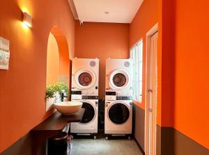 Duas máquinas de lavar roupa num quarto com paredes cor-de-laranja em Kin Wander Tan Quy em Cidade de Ho Chi Minh