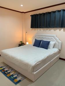 a bedroom with a large white bed with blue pillows at BAAN OZONE in Hat Yai