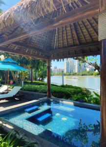a swimming pool under a straw umbrella next to a river at Pullman Haikou in Haikou