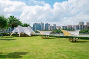 Tres tiendas de campaña en un campo con una ciudad en el fondo en Pullman Haikou en Haikou