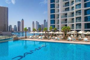 a swimming pool with chairs and umbrellas and a building at Canal View Studio Apartments - DAMAC Prive Business Bay in Dubai