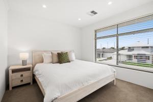 a white bedroom with a bed and a window at Modern Minimalistic Home in Perth