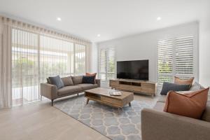 a living room with couches and a flat screen tv at Modern Minimalistic Home in Perth