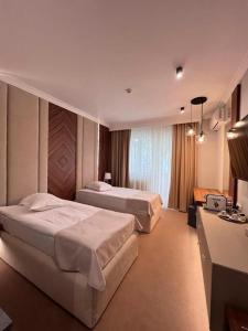 um quarto de hotel com duas camas e uma grande janela em Hotel Castel em Râmnicu Vâlcea