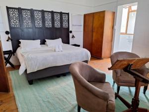 a bedroom with a bed and two chairs and a table at Yield House and Cottages in Port Nolloth