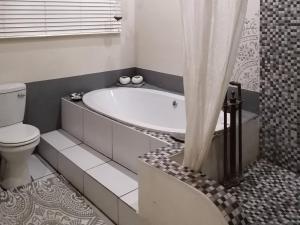 a bathroom with a bath tub and a toilet at Yield House and Cottages in Port Nolloth