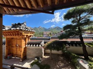 a view of a building with a tree and mountains at Sirakdang Hanok in Seoul