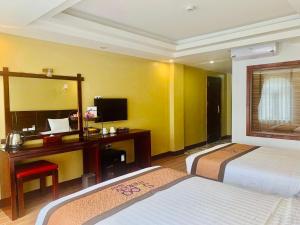 a hotel room with two beds and a desk and a mirror at Sapa Melody Hotel in Sa Pa