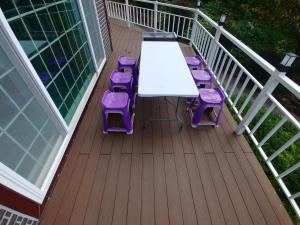 una mesa blanca y taburetes púrpura en una cubierta en Beljari Pension en Tongyeong