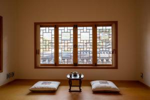 ソウルにあるSirakdang Hanokの枕2つと窓の前にテーブルが備わる客室です。