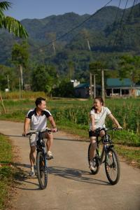 a man and a woman riding bikes down a road at The BanBa Jungle Lodge in Làng Hoa (2)