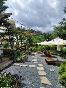 大叻的住宿－Ma Lá Glamping Đà Lạt，花园中一条带岩石和遮阳伞的小路