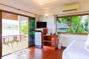een slaapkamer met een bed en een balkon met een televisie bij Lamai bayview boutique resort in Koh Samui 