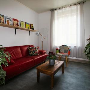 a living room with a red couch and a table at Maison Tarrade in Châteauneuf-la-Forêt