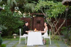 Ein Mann und eine Frau sitzen an einem Tisch mit einem Kuchen in der Unterkunft Shining Riverside Hoi An Boutique & Spa in Hoi An