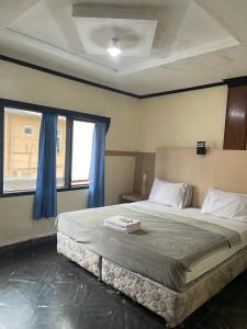 Schlafzimmer mit einem großen Bett und blauen Vorhängen in der Unterkunft Losmen Sibayak Berastagi in Berastagi