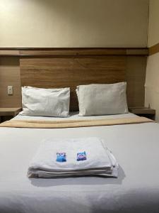 un letto bianco con due asciugamani sopra di Losmen Sibayak Berastagi a Berastagi