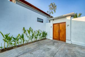 a white house with a wooden door and plants at *NEW* Modern 3BD Villa in quiet Perenenan! in Canggu