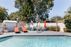 uma piscina com cadeiras e guarda-sóis ao lado de uma cerca em Flamingo Bay Coastal Oasis: Modern Comforts, Heated Pool w/ BBQ em Tampa