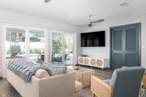 uma sala de estar com um sofá e uma televisão em Flamingo Bay Coastal Oasis: Modern Comforts, Heated Pool w/ BBQ em Tampa
