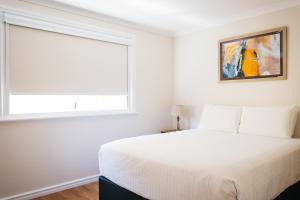 a white bedroom with a bed and a window at Owen's Hideaway by the BnB Collection in Albany