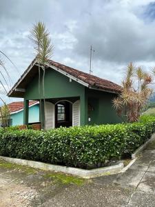 una casa verde con una palmera delante de ella en Chale linda vista Penedo, en Itatiaia