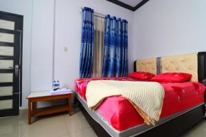 um quarto com uma cama com almofadas vermelhas e uma mesa em Wisma Barokah em Tebingtinggi