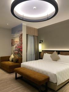 um quarto com uma grande cama branca e um sofá em Posto Dormire Sudirman em Jakarta