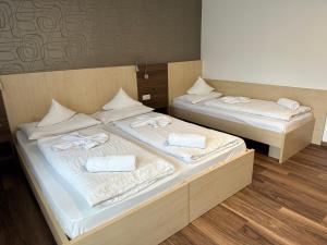 two beds in a room with white sheets and towels at Hotel Klammer in Vipiteno