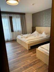 two beds in a room with wooden floors at Hotel Klammer in Vipiteno