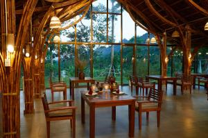 a dining room with tables and chairs and a large window at The BanBa Jungle Lodge in Làng Hoa (2)