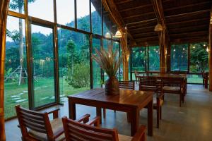 een eetkamer met tafels en stoelen en grote ramen bij The BanBa Jungle Lodge in Làng Hoa (2)