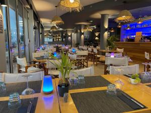 une salle à manger avec des tables, des chaises et des lumières dans l'établissement Acadie Saint Victor - Hôtel restaurant - Face mer - Chatelaillon plage, à Châtelaillon-Plage