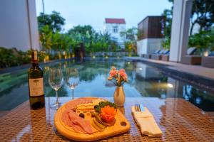 een tafel met een bord eten en een fles wijn bij Cozy An Boutique Hotel Hoian in Hội An