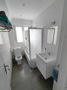 Baño blanco con aseo y lavamanos en SM18 Apartment, en San Sebastián